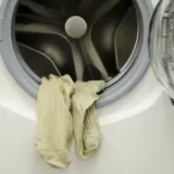 Para skarpetek wisi na drzwiach pralki. Mimo czyszczenia, pralka śmierdzi, a skarpetki wyglądają na zużyte.