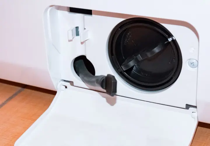 Otwarta klapka z wężykiem do spuszczania wody i czarną zakrętką filtra. Dowiedz się, jak wyczyścić filtr w pralce Whirlpool, aby zapewnić jej sprawność.