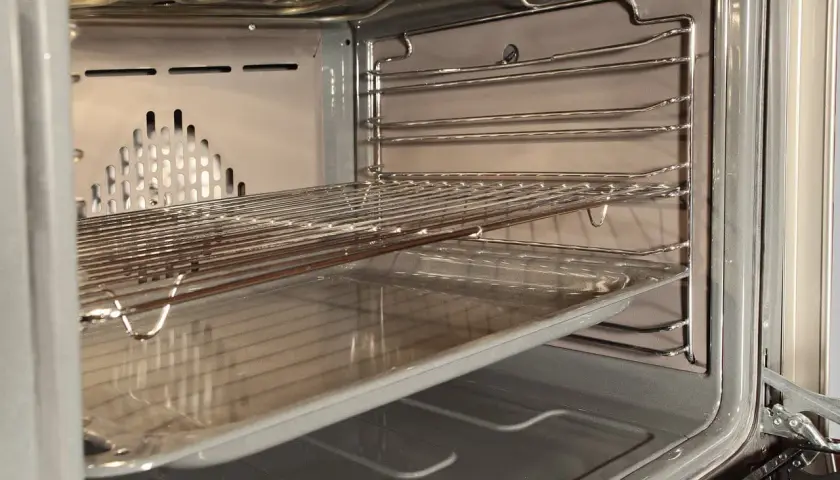 Wnętrze piekarnika z rusztami i blachą, gotowe do czyszczenia katalitycznego.